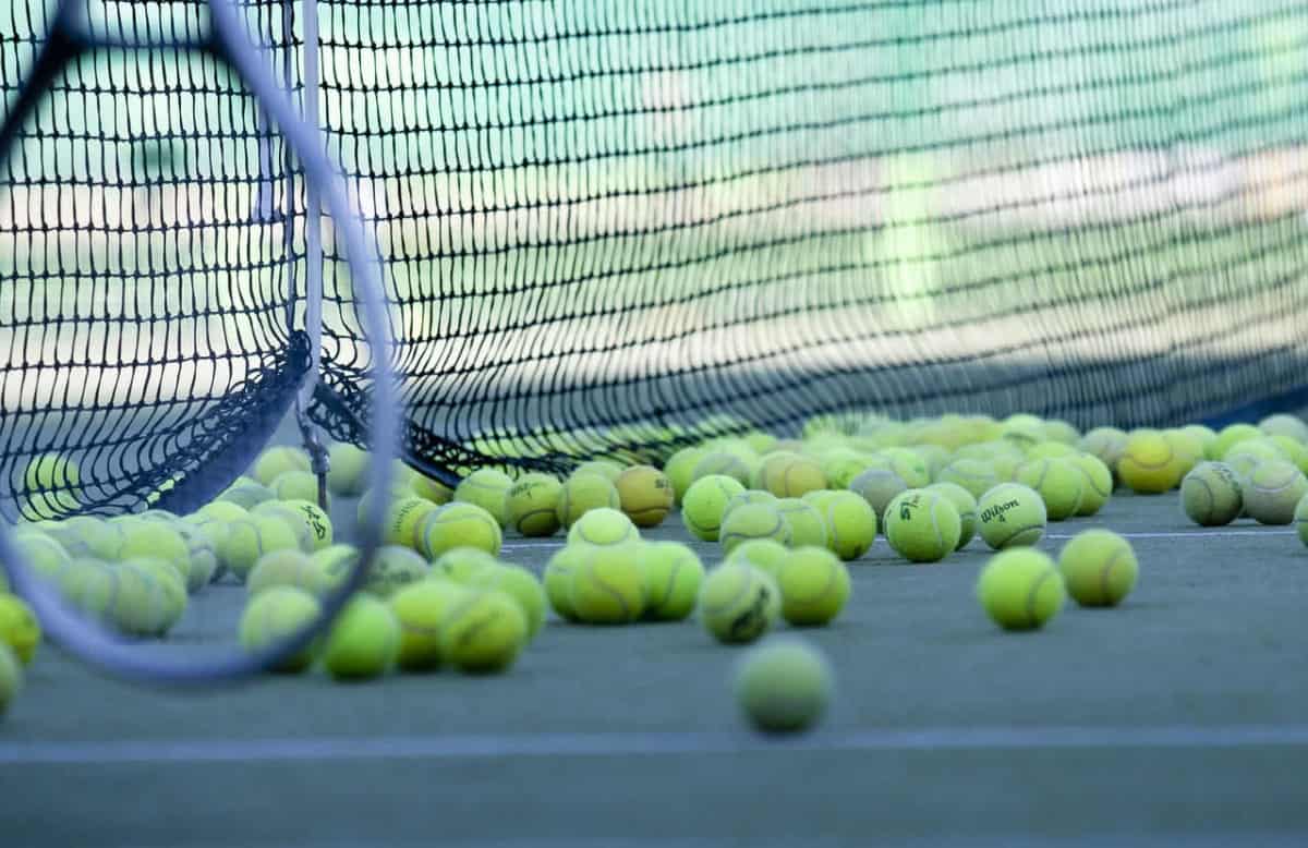 Raquete de tenis e varias bolas na rede
